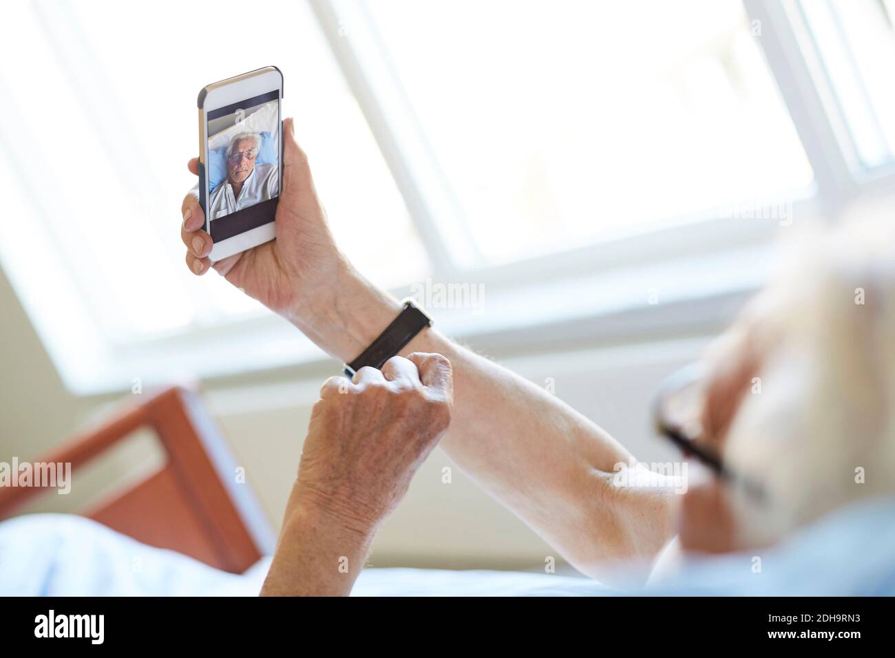 Image rognée d'un homme âgé prenant un selfie avec un smartphone dans la salle d'hôpital Banque D'Images