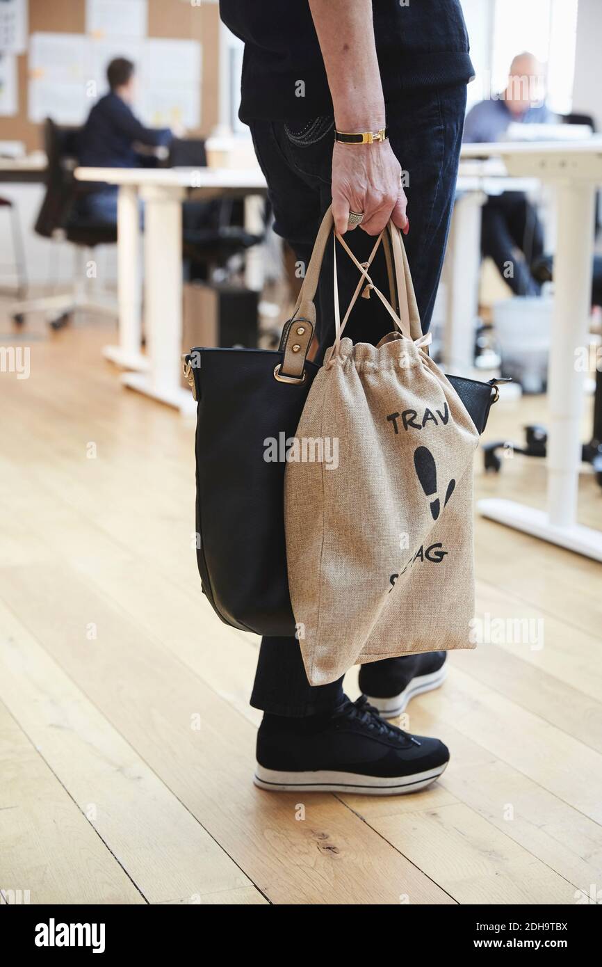 Section basse de femme d'affaires senior à la mode debout avec sac à main  et sac sur parquet au bureau Photo Stock - Alamy