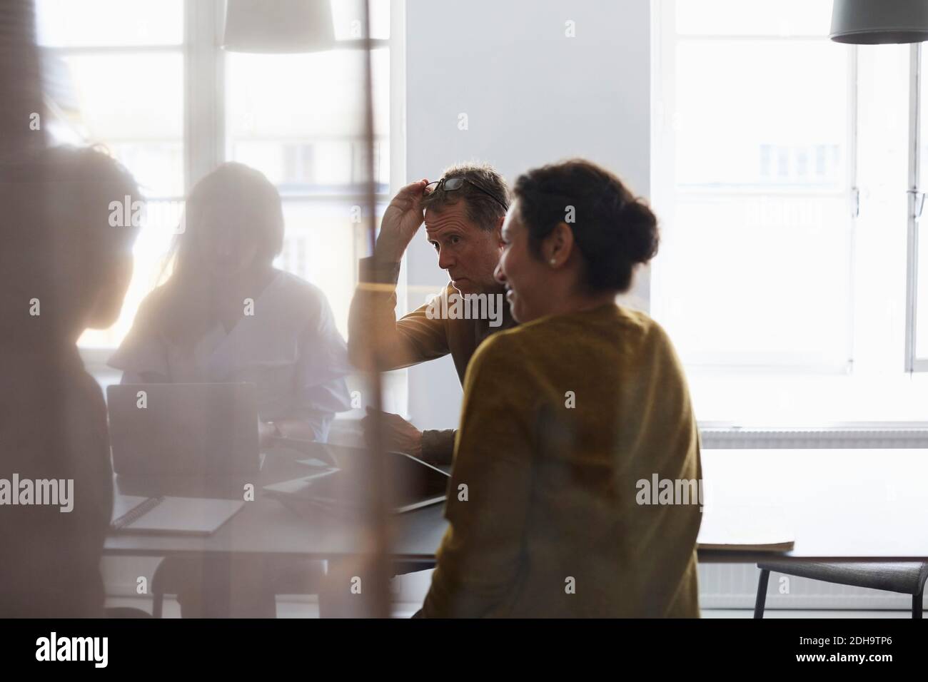 Équipe créative assise dans la salle du conseil d'administration, vue depuis le verre à bureau Banque D'Images