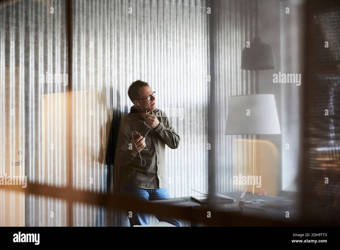 Homme d'affaires mature parlant sur un smartphone via un casque d'origine verre Banque D'Images