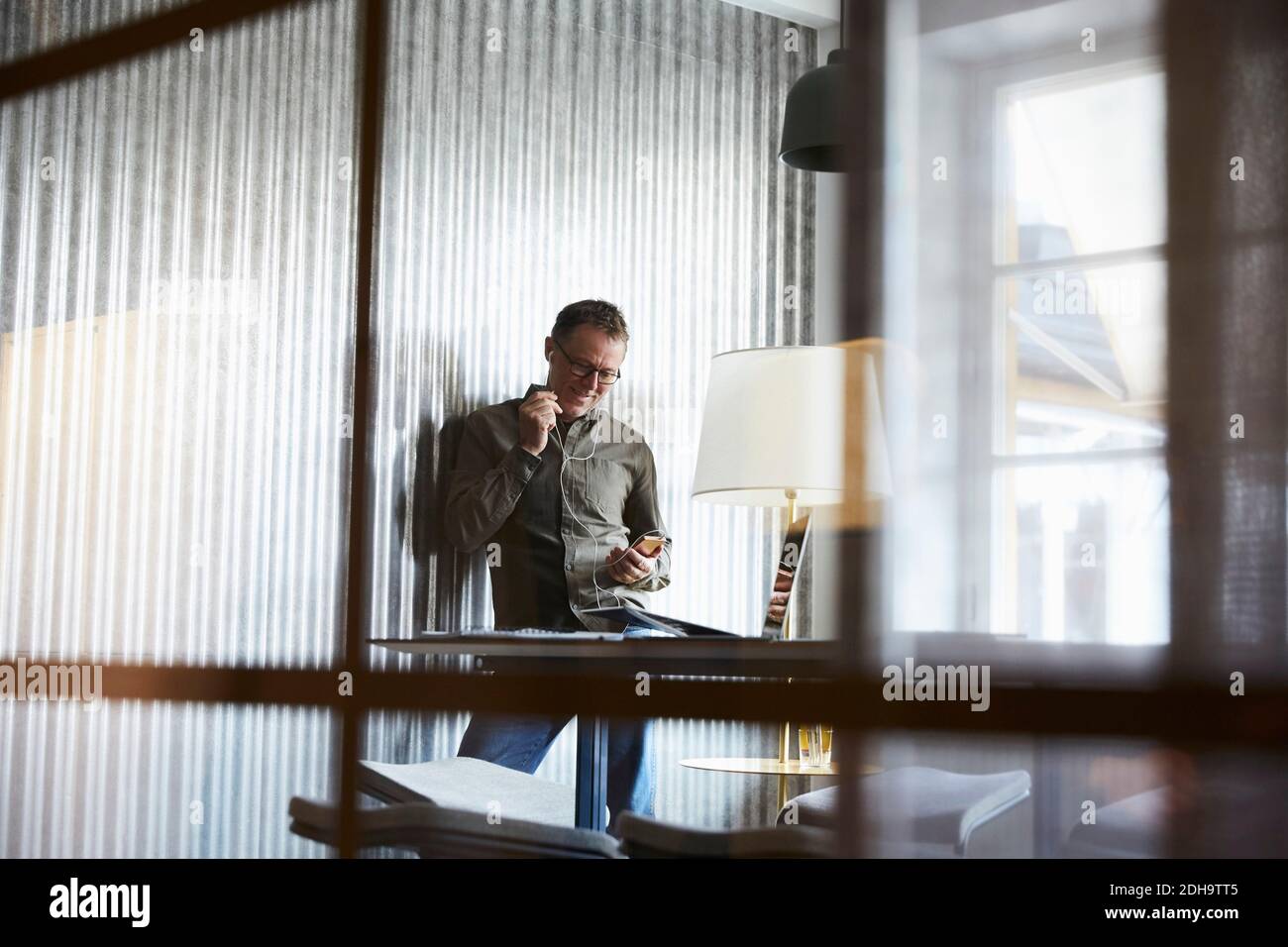 Homme d'affaires mature parlant sur un smartphone via un casque d'origine verre au bureau créatif Banque D'Images