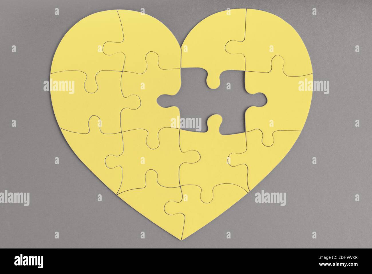 Couleur tendance de l'année 2021. Gris ultime et jaune lumineux. Pièce manquante de puzzle en forme de coeur. Amour, charité, concept de don Banque D'Images