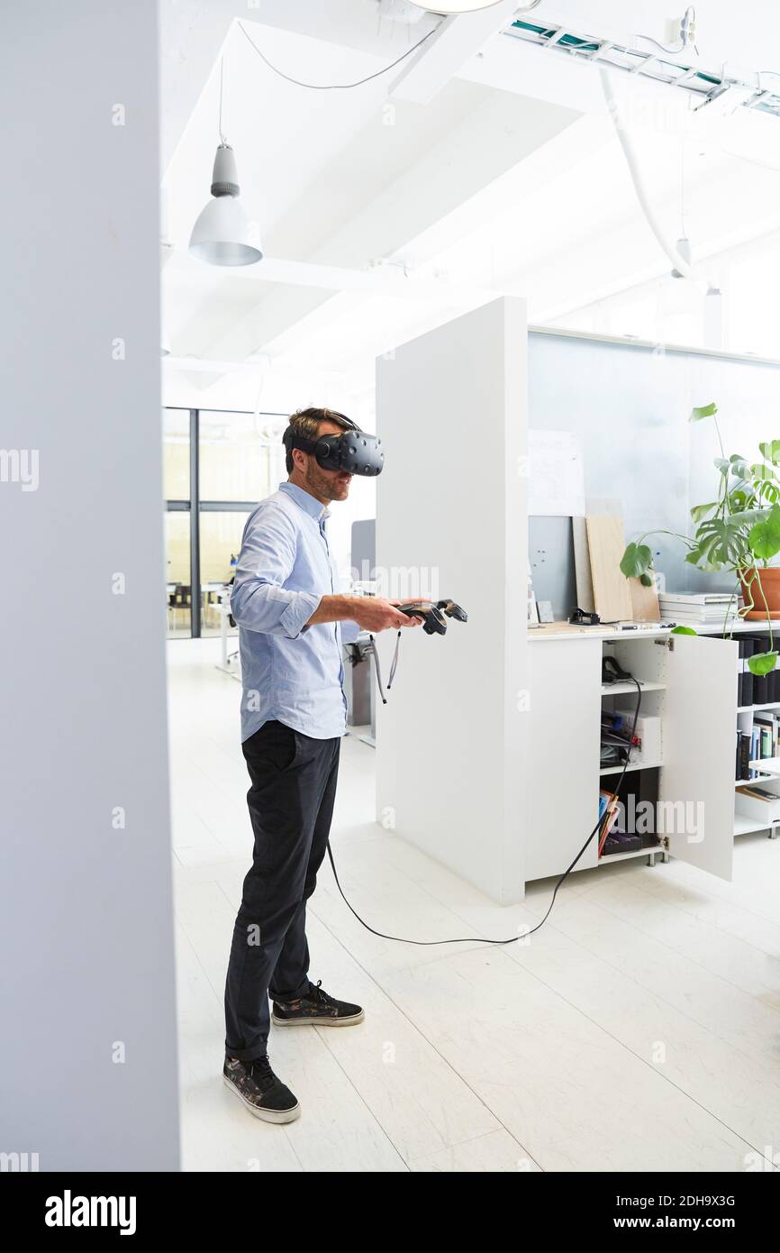 Homme d'affaires utilisant le stimulateur de réalité virtuelle pendant qu'il se trouve dans un bureau créatif Banque D'Images