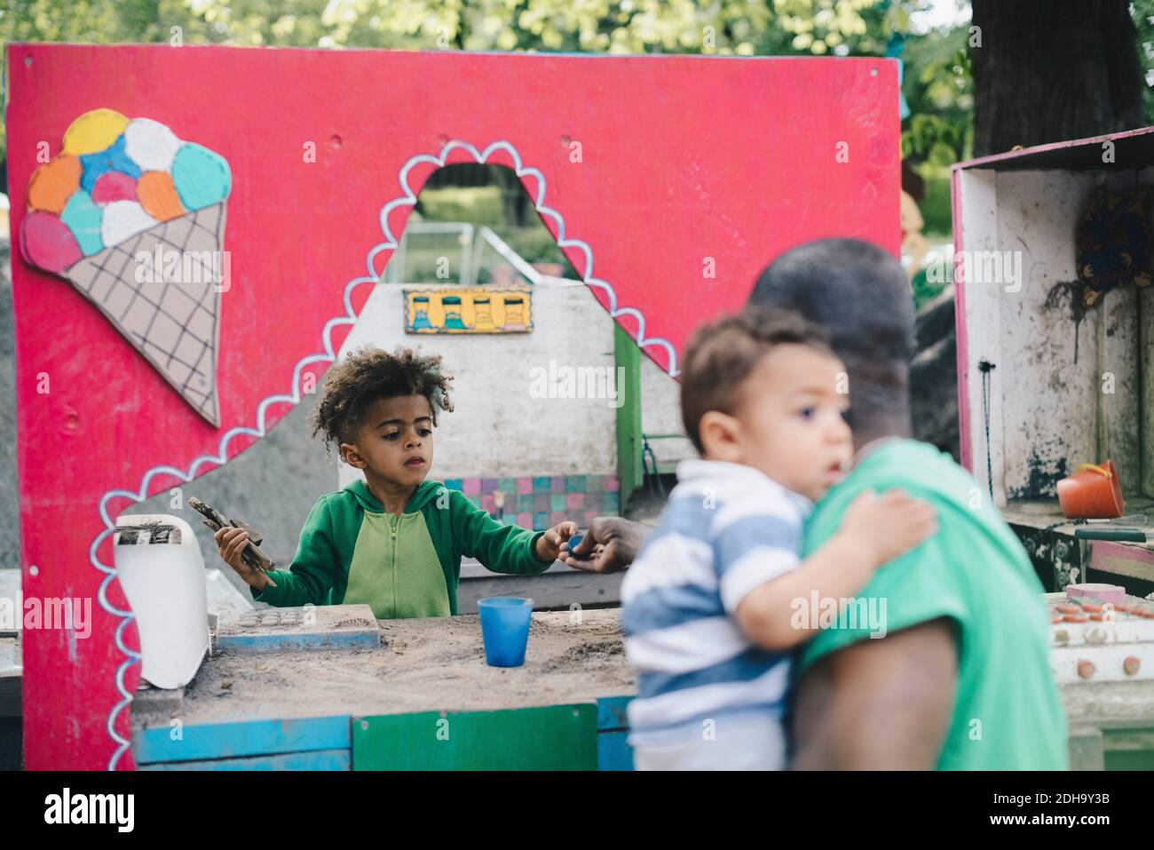 Père jouant avec des enfants dans un stand abandonné au parc Banque D'Images
