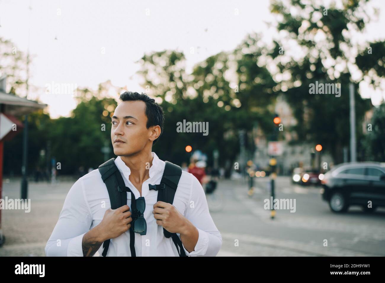 Jeune homme regardant loin avec un sac en ville Banque D'Images