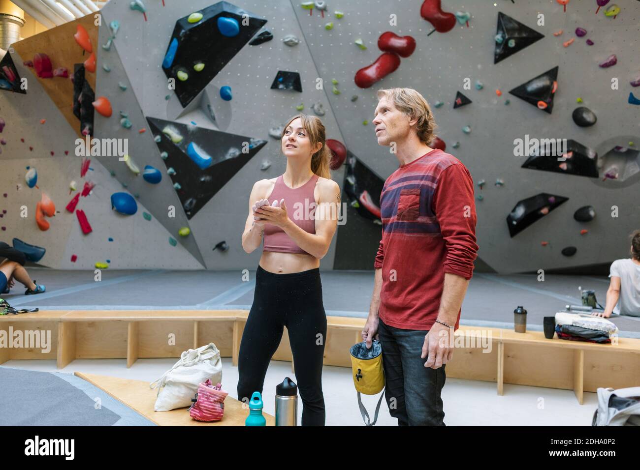 Instructeur d'âge mûr avec une étudiante qui regarde tout en se tenant debout salle de sport Banque D'Images