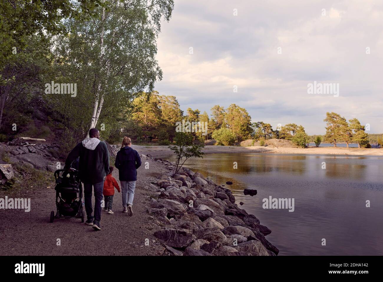 Vue arrière de la famille marchant sur le bord du lac contre le ciel Banque D'Images