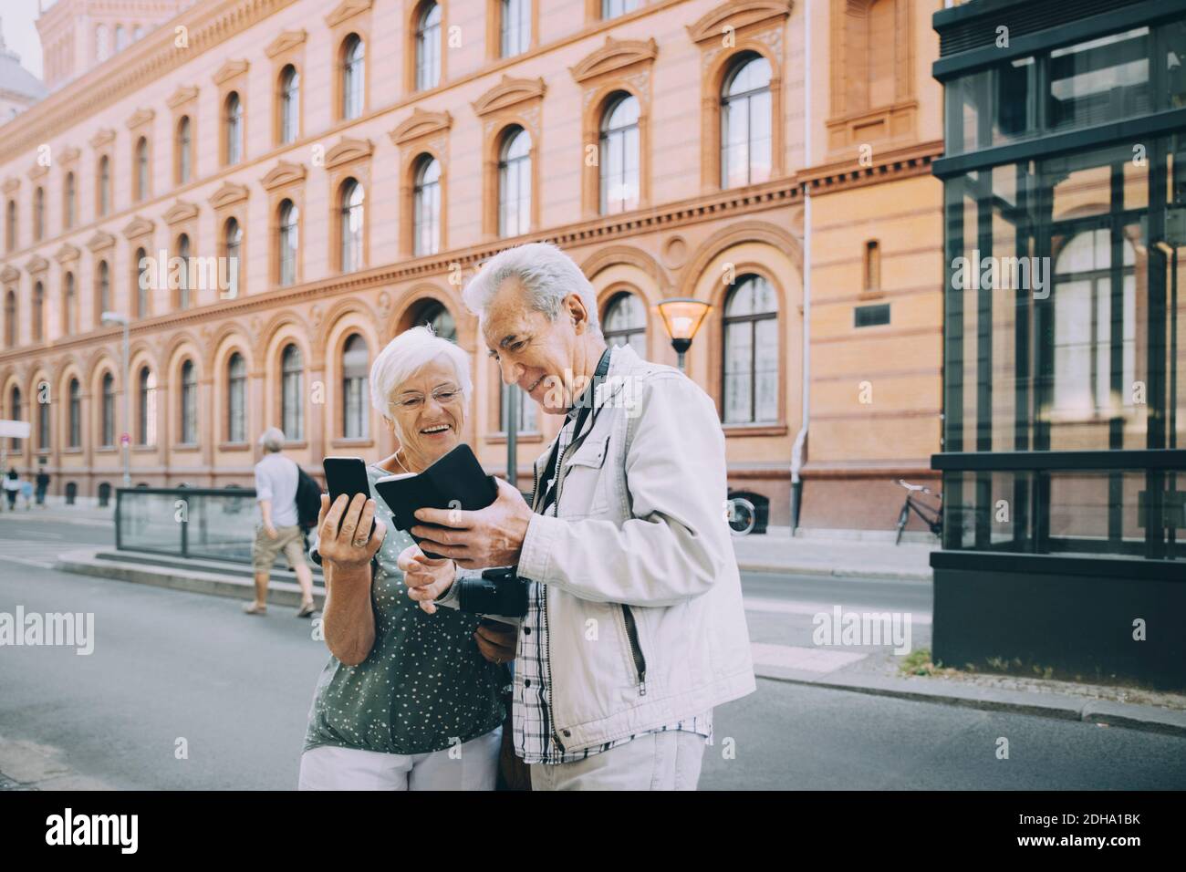 Souriant homme et femme touriste senior en utilisant le smartphone pendant explorer en ville Banque D'Images
