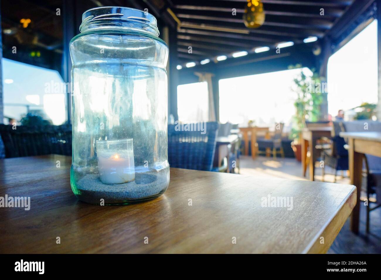 Une bougie illuminée dans le pot en verre sur la table Banque D'Images