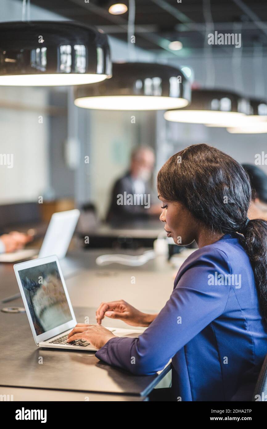 Femme d'affaires travaillant sur un ordinateur portable assis à une table au bureau Banque D'Images
