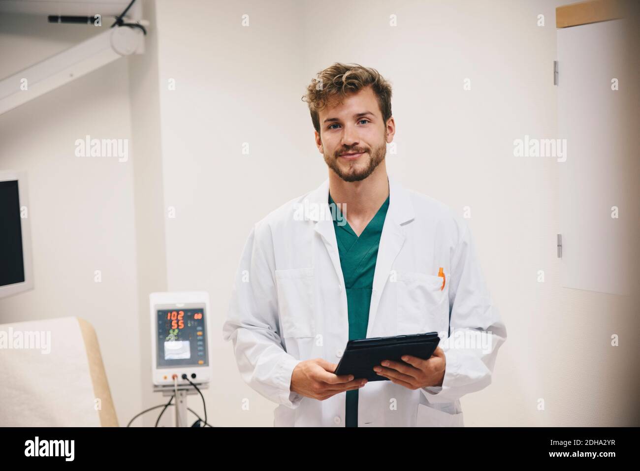 Portrait d'un médecin homme confiant debout avec une tablette numérique à hôpital Banque D'Images