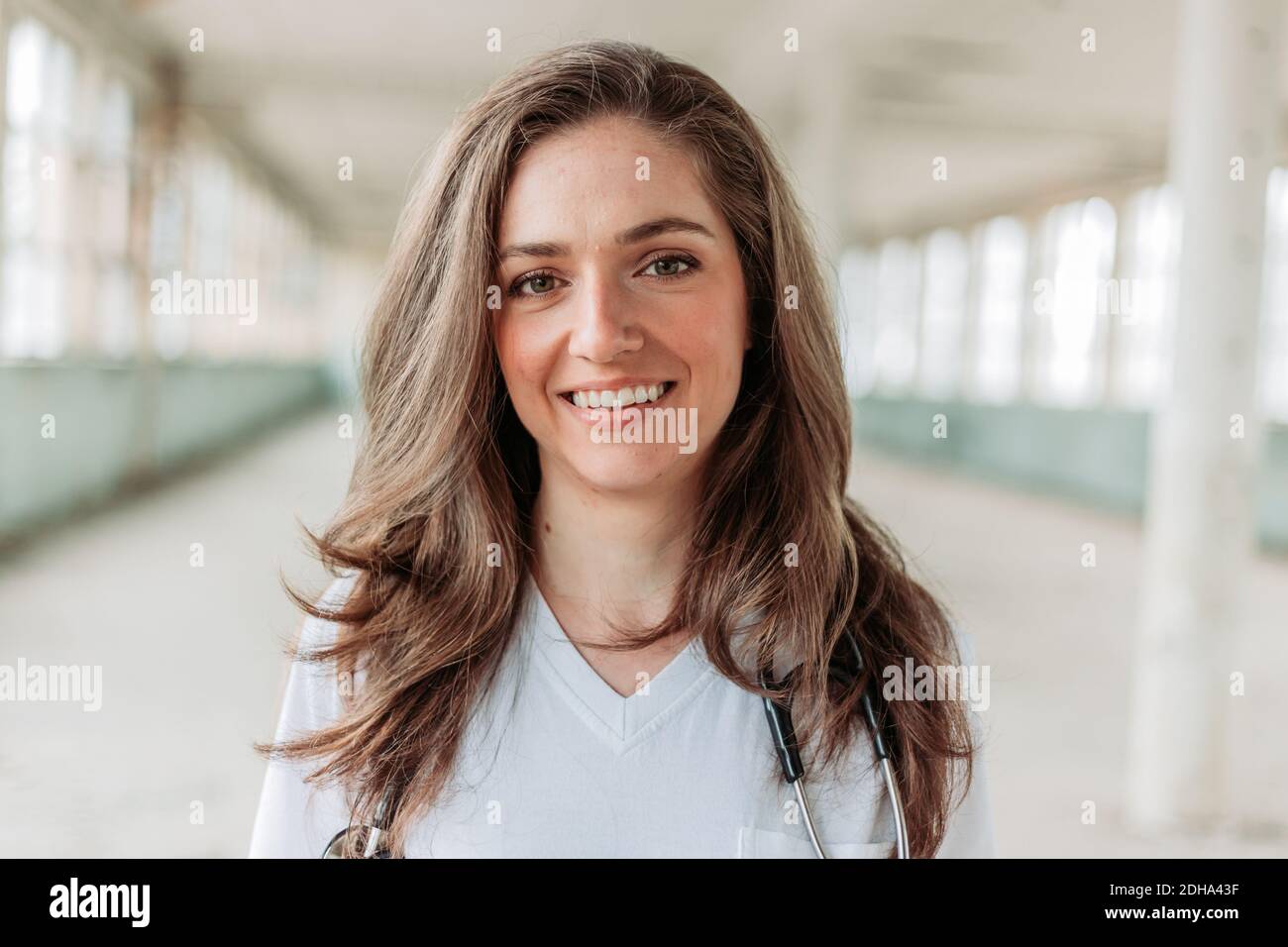 Jeune femme blonde médecin souriant. Arrière-plan flou. Lutte contre le virus Corona Banque D'Images