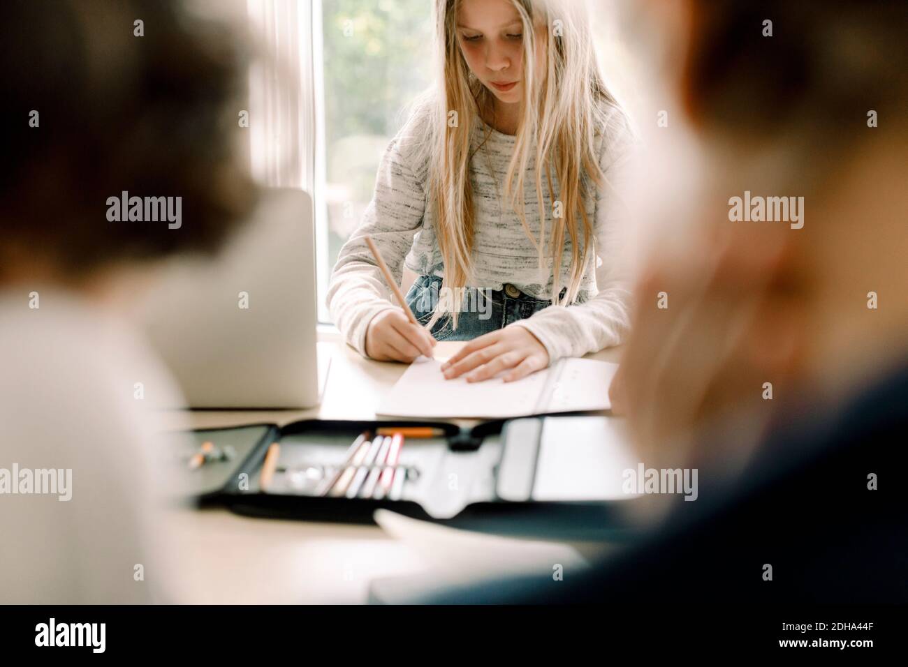 Female student writing in book at table Banque D'Images