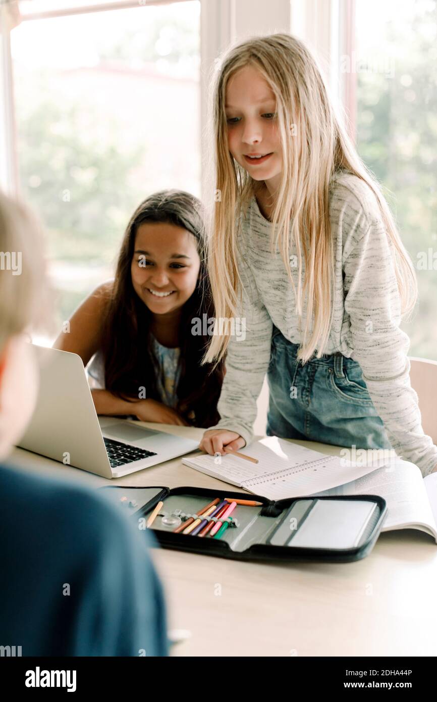 Une étudiante qui regarde en se tenant debout près d'un ami en classe Banque D'Images