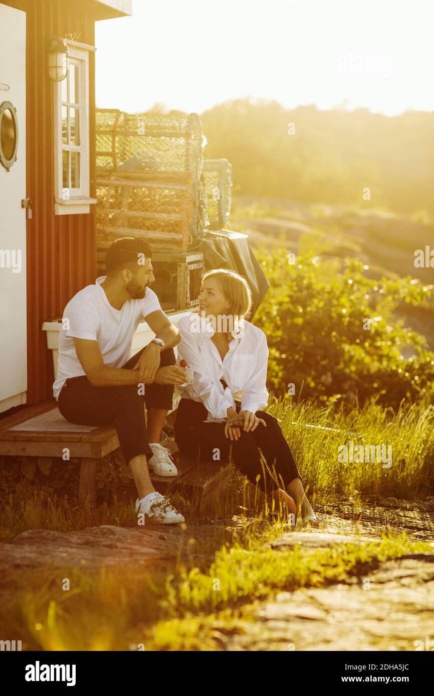 Un jeune couple parle en étant assis dans une cabane en rondins sous le soleil jour Banque D'Images