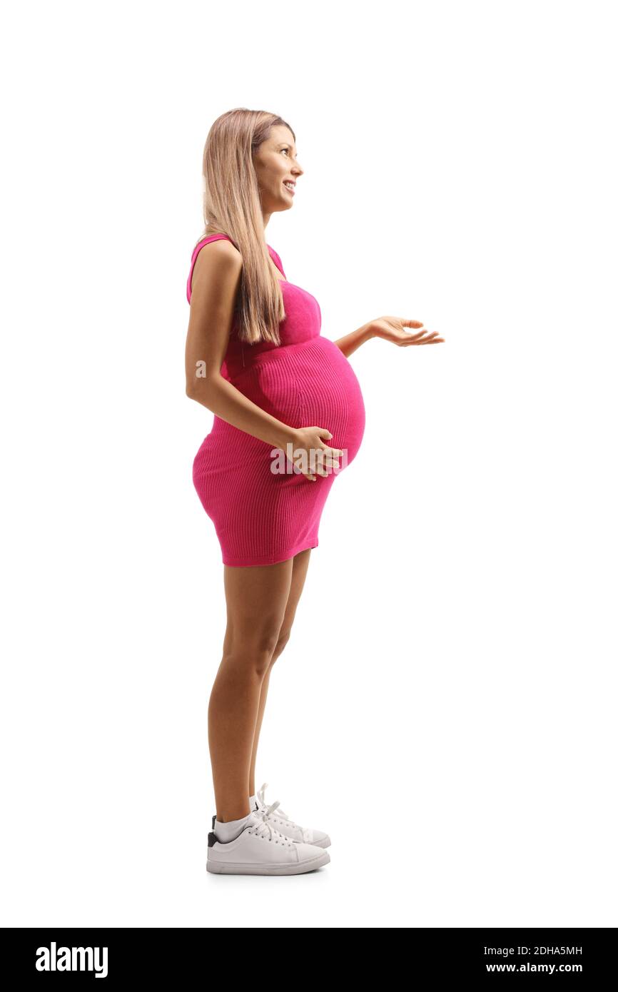 Photo de profil pleine longueur d'une jeune femme enceinte dans robe rose isolée sur fond blanc Banque D'Images