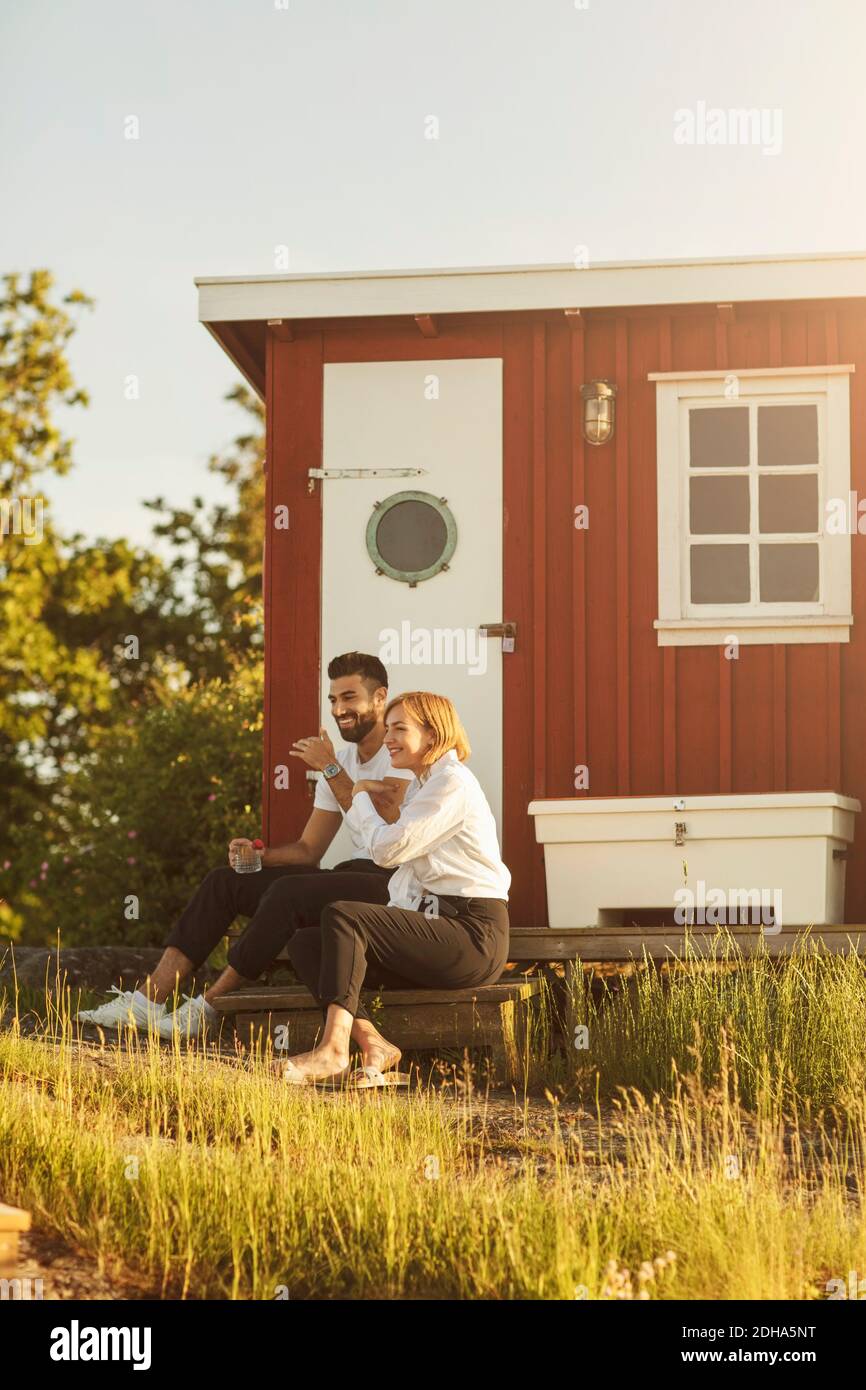 Heureux couple assis à la cabane en rondins le jour ensoleillé Banque D'Images