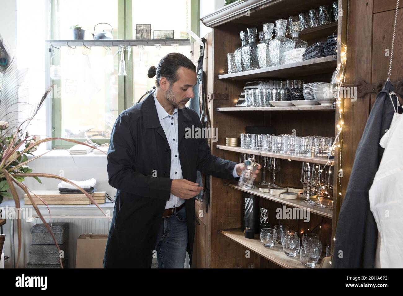 Client homme mature qui choisit un contenant en verre dans une étagère du magasin Banque D'Images