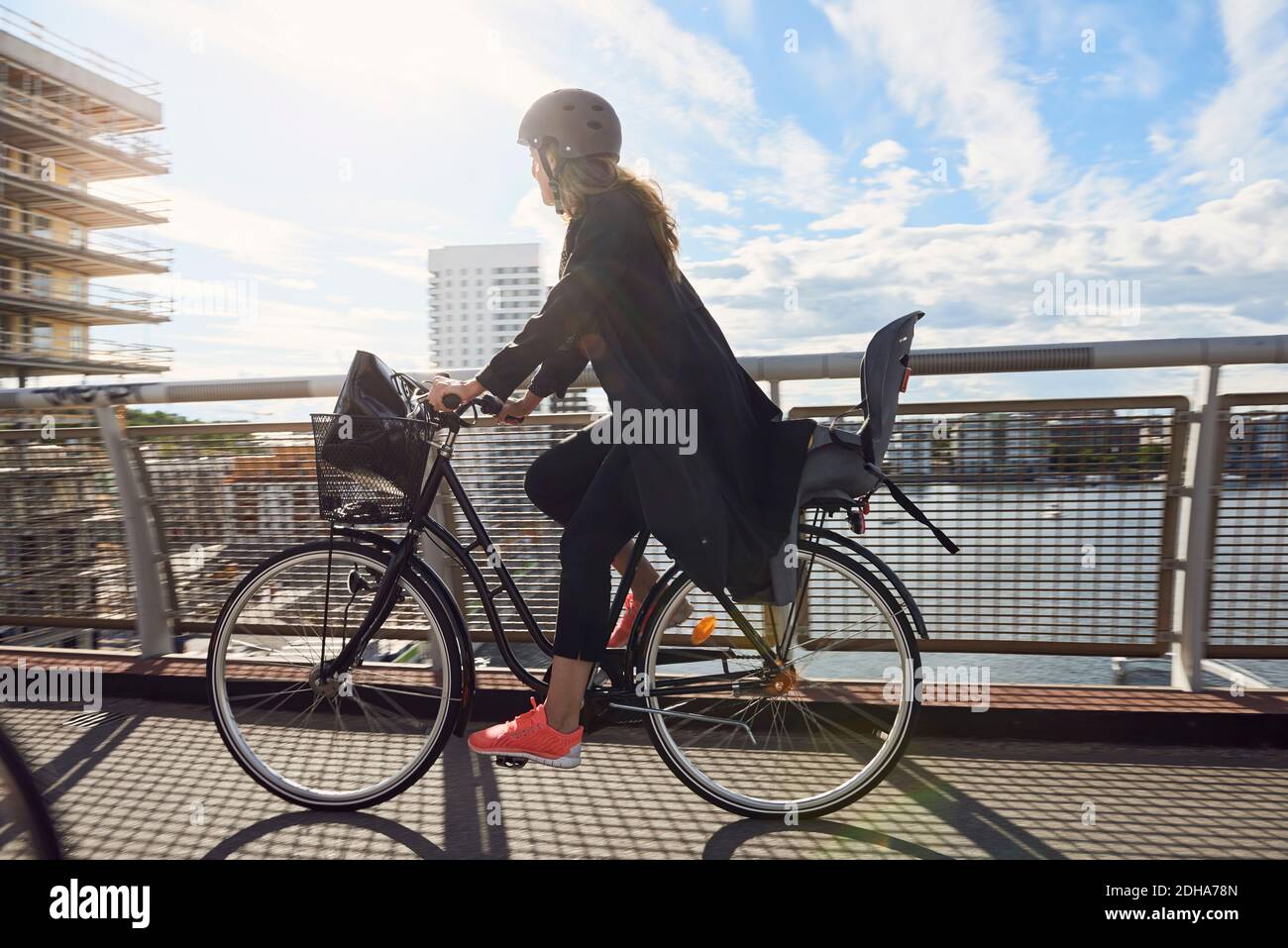 Vue latérale d'une femme mûre en vélo sur la passerelle contre le ciel Banque D'Images