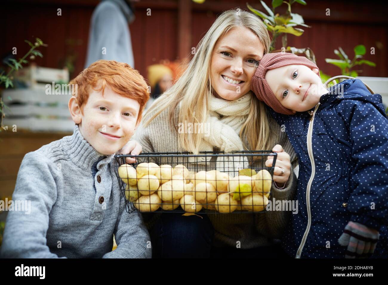 Portrait de la mère avec panier de pommes de terre assis par les enfants à cour Banque D'Images