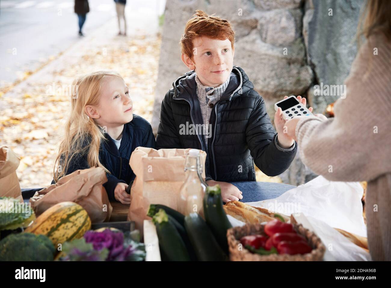 Les frères et sœurs masculins et féminins avec lecteur de carte de crédit sur le marché calage Banque D'Images