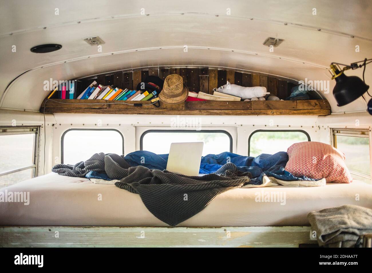 Ordinateur portable et couverture froissés sur le lit dans le véhicule de camping Banque D'Images