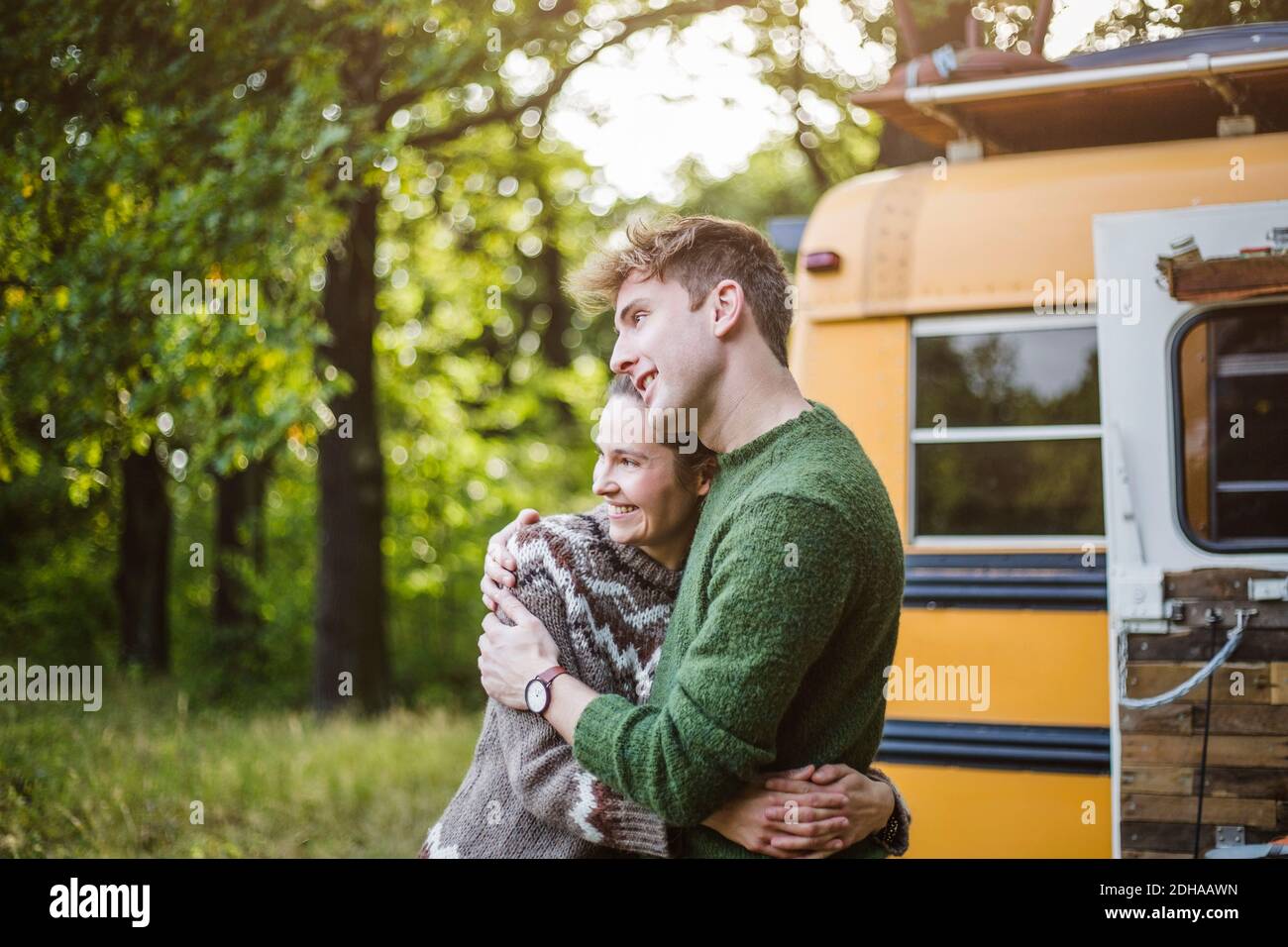 Un couple de jeunes adultes souriant s'embrasse tout en appréciant le camping dans la forêt Banque D'Images