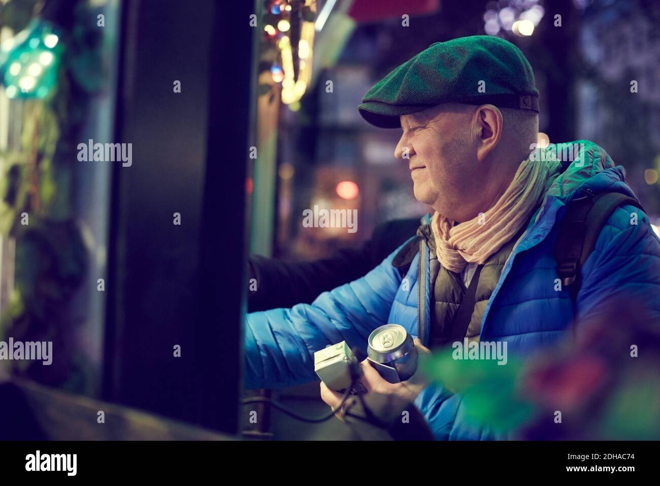 Homme senior souriant tenant des boissons au stand de concession en ville Banque D'Images