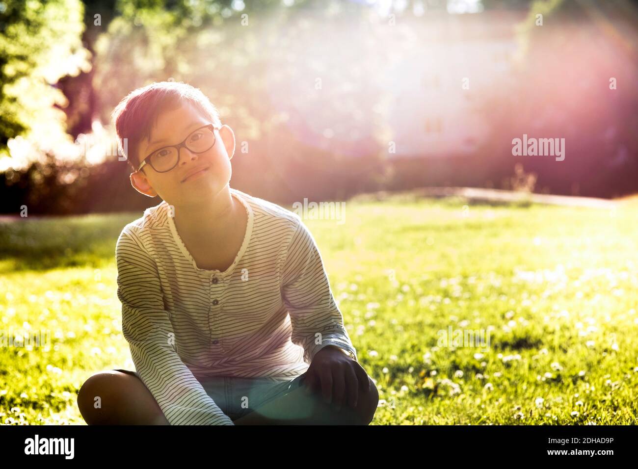 Portrait d'un garçon handicapé assis sur un terrain herbeux pendant le soleil jour Banque D'Images