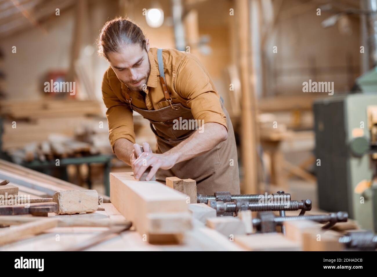 Beau charpentier travaillant avec un bois, plantant un bar avec un avion dans l'atelier de menuiserie Banque D'Images