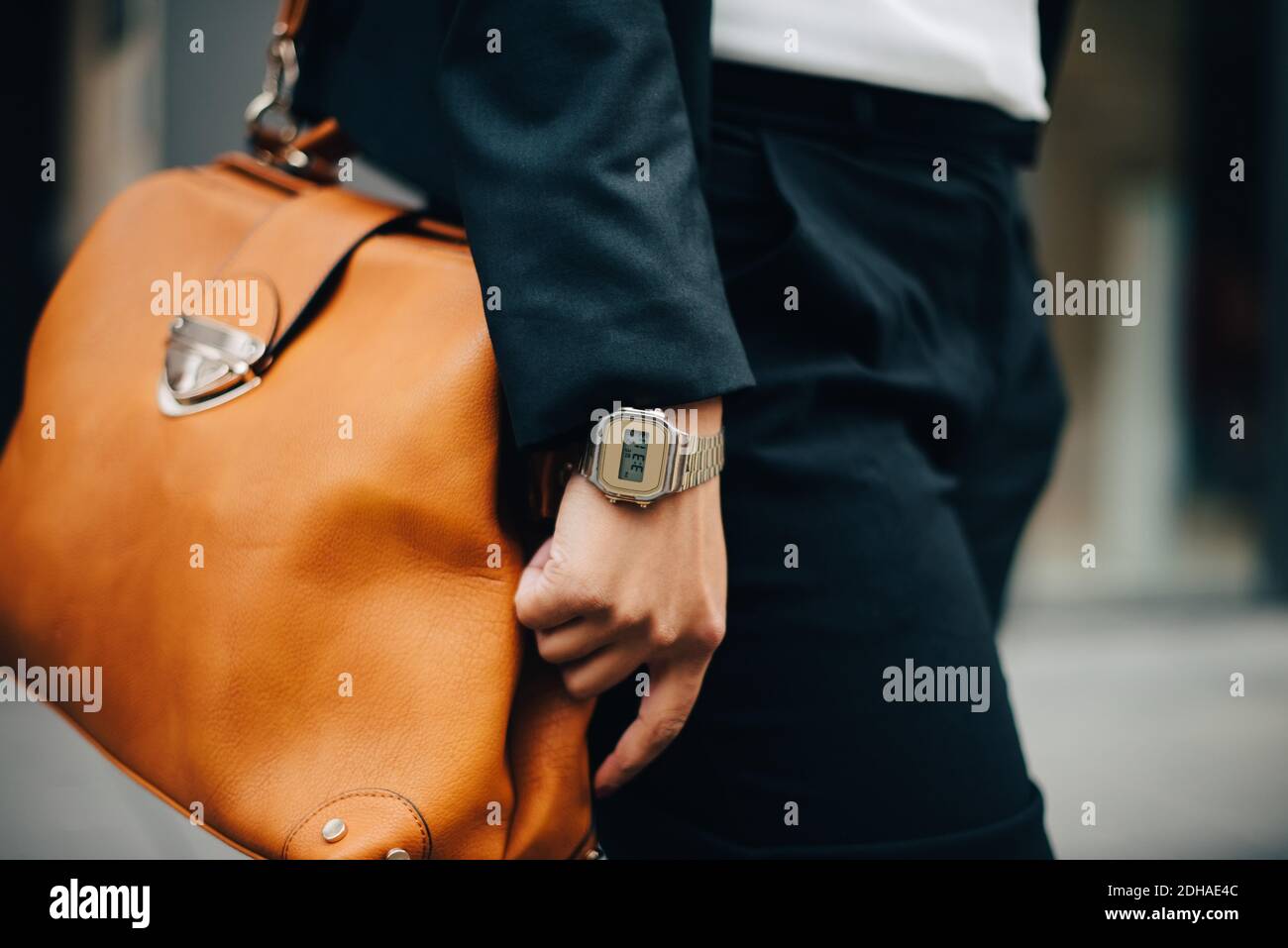 Milieu de section de femme d'affaires avec sac à main orange debout dans la ville Banque D'Images