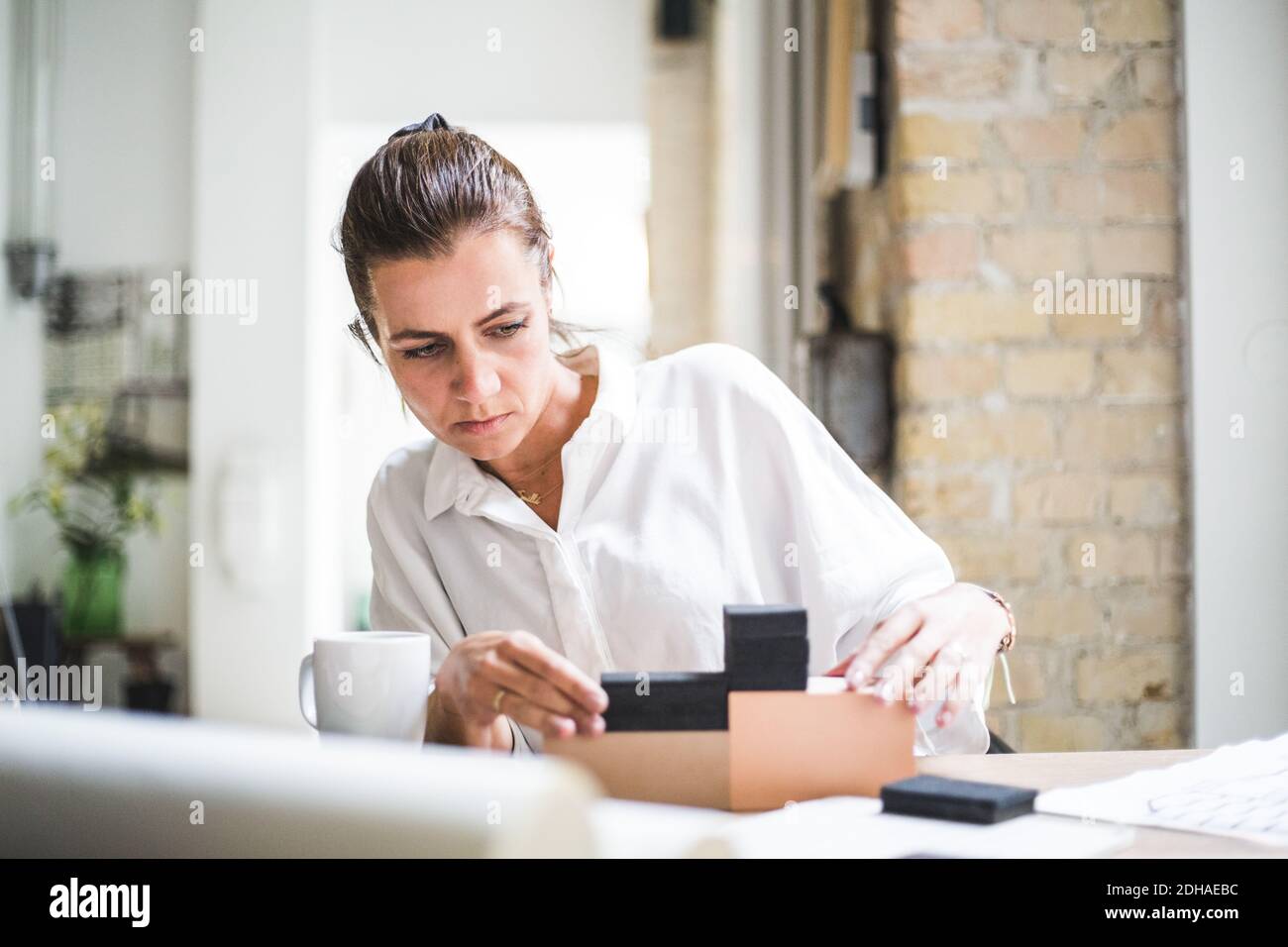 Femme design professionnel travaillant avec des boîtes tout en étant assis à la maison bureau Banque D'Images