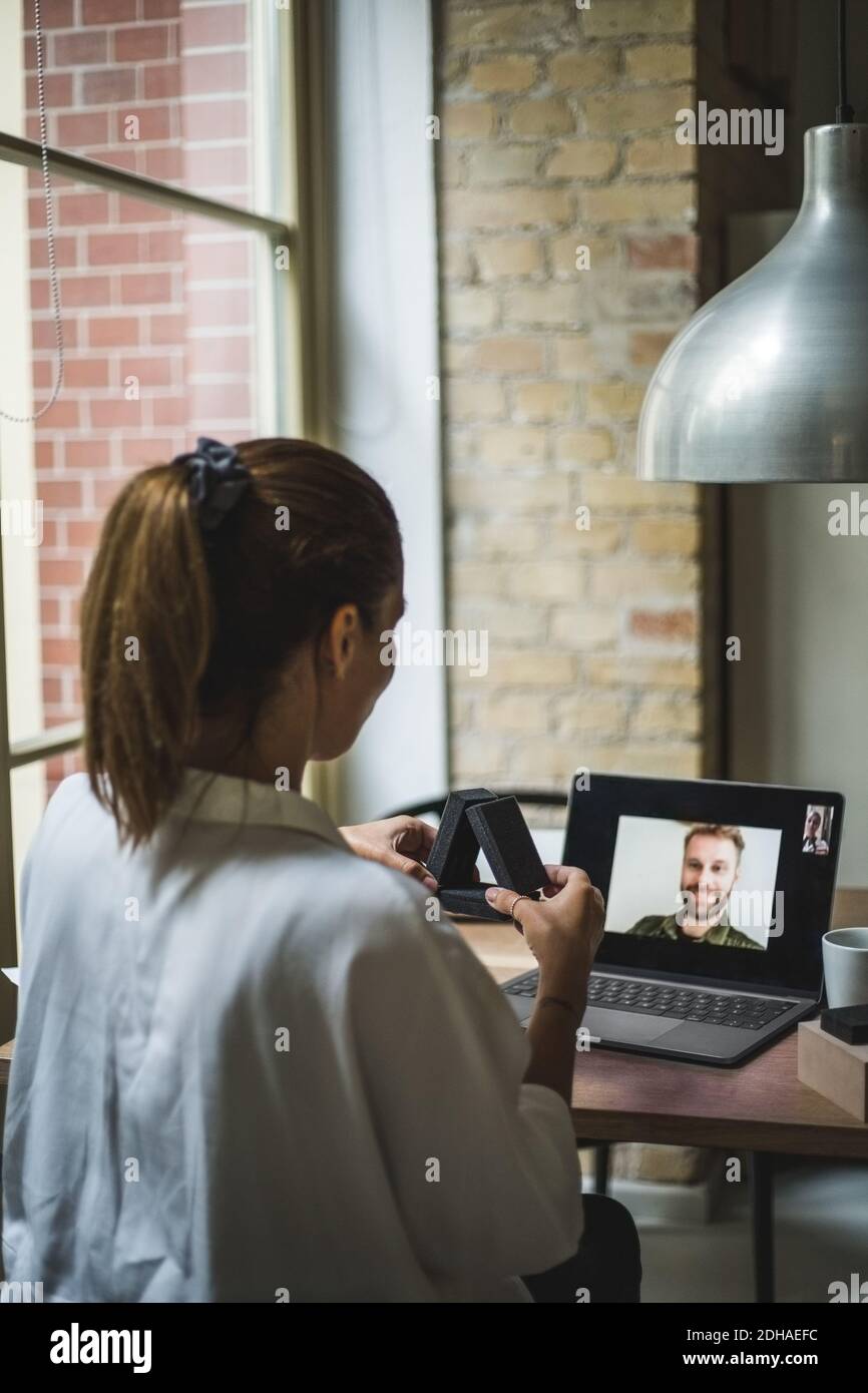 Vue arrière du mannequin tenant le modèle tout en parlant collègue par appel vidéo au bureau à domicile Banque D'Images