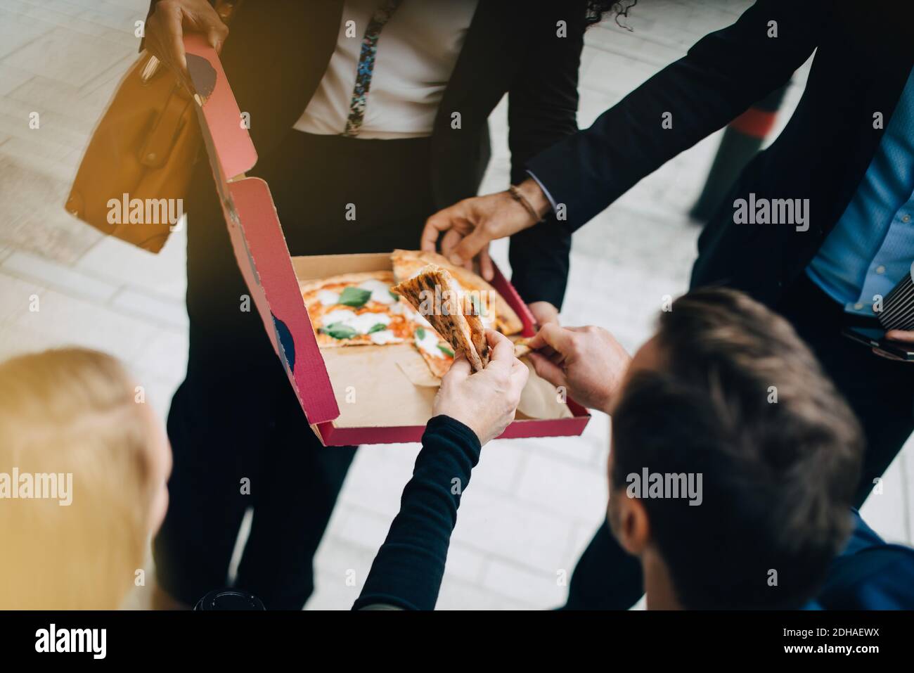 Vue en grand angle des collègues d'affaires qui mangent de la pizza box dans la ville Banque D'Images
