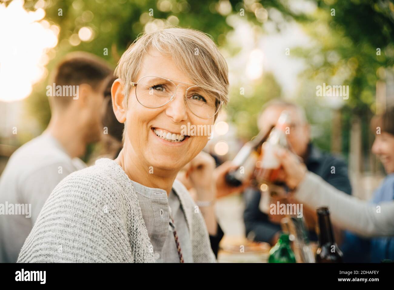 Portrait d'une femme mûre heureuse assise avec des amis à social rassemblement Banque D'Images