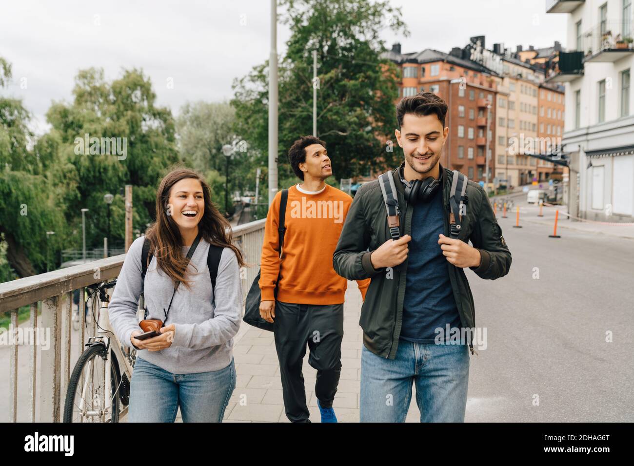 Des amis souriants marchent dans la rue tout en explorant la ville pendant les vacances Banque D'Images