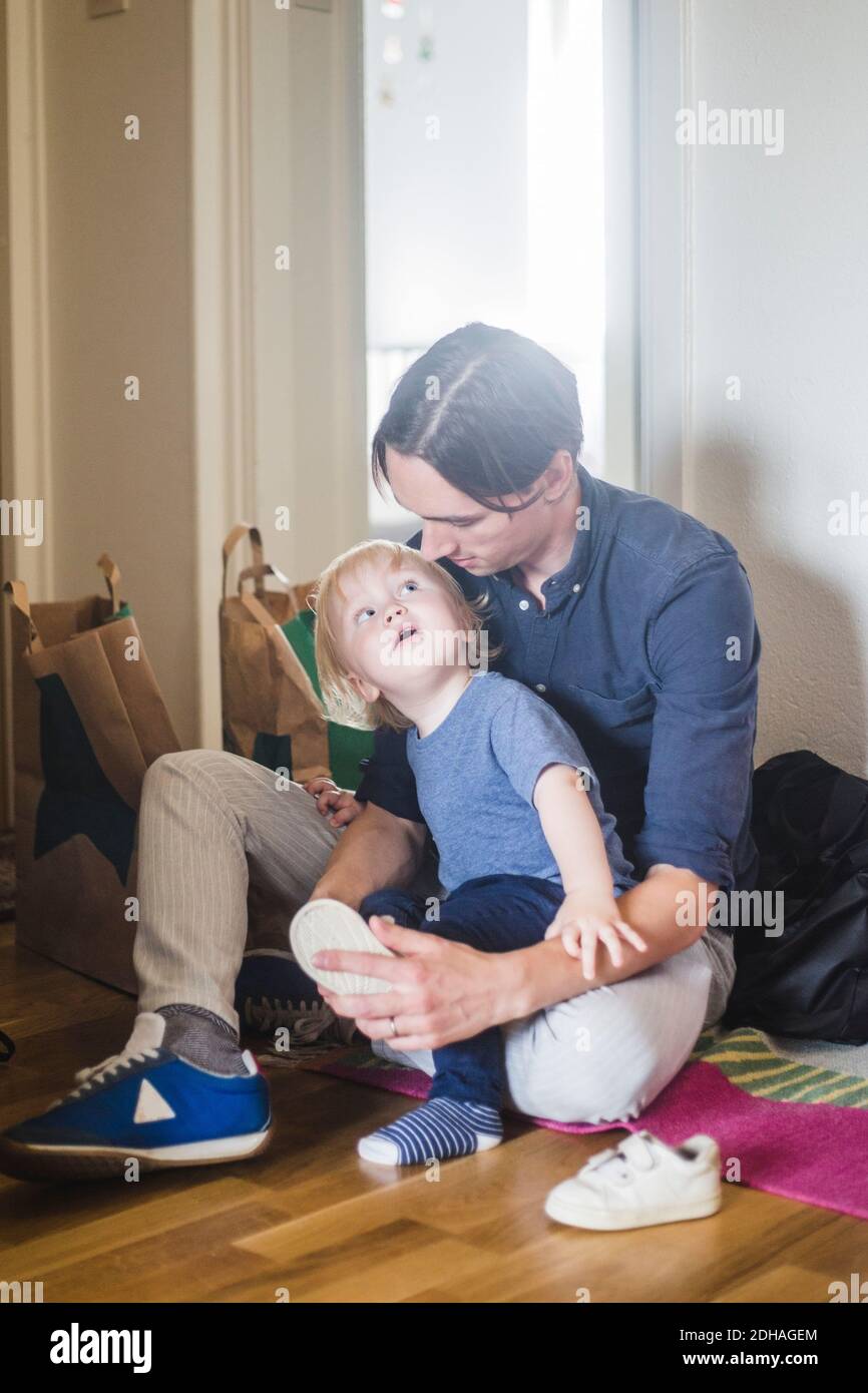 Bébé garçon regardant le père aider à porter des chaussures Banque D'Images