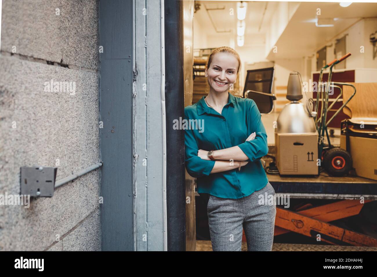 Portrait d'une femme d'affaires souriante debout bras croisés dans un nouveau bureau Banque D'Images