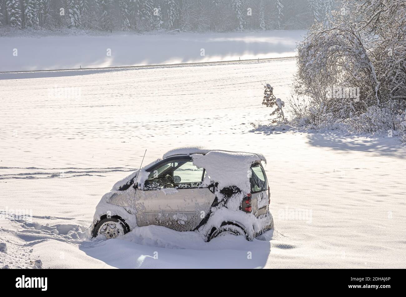 Voiture accidentelle ou tout-terrain de la marque Smart. Verunfaltes und von der Straße abgekommenes eingeschneites Auto der Marke Smart. Banque D'Images