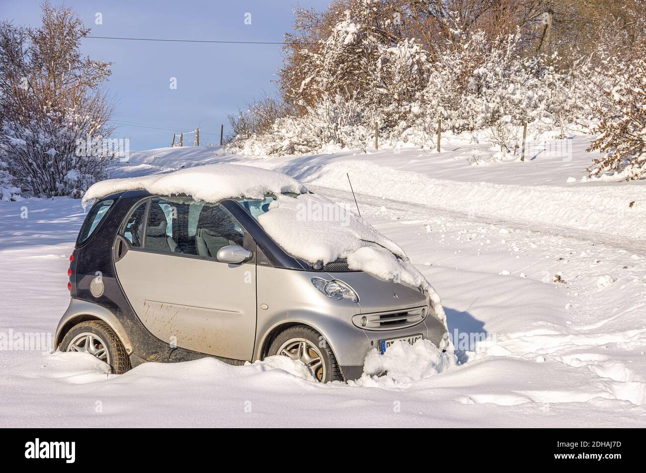 Voiture accidentelle ou tout-terrain de la marque Smart. Verunfaltes und von der Straße abgekommenes eingeschneites Auto der Marke Smart. Banque D'Images