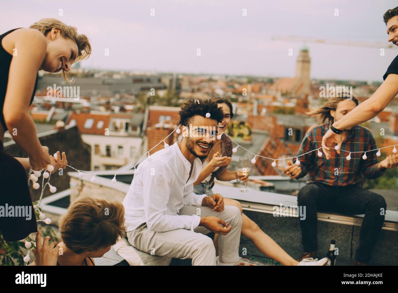 Des amis ludiques s'amusent avec la lumière des cordes sur la terrasse sur le toit fête Banque D'Images