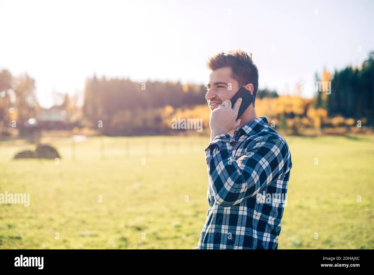 Agriculteur de sexe masculin de taille moyenne, parlant au téléphone mobile sur le terrain Banque D'Images