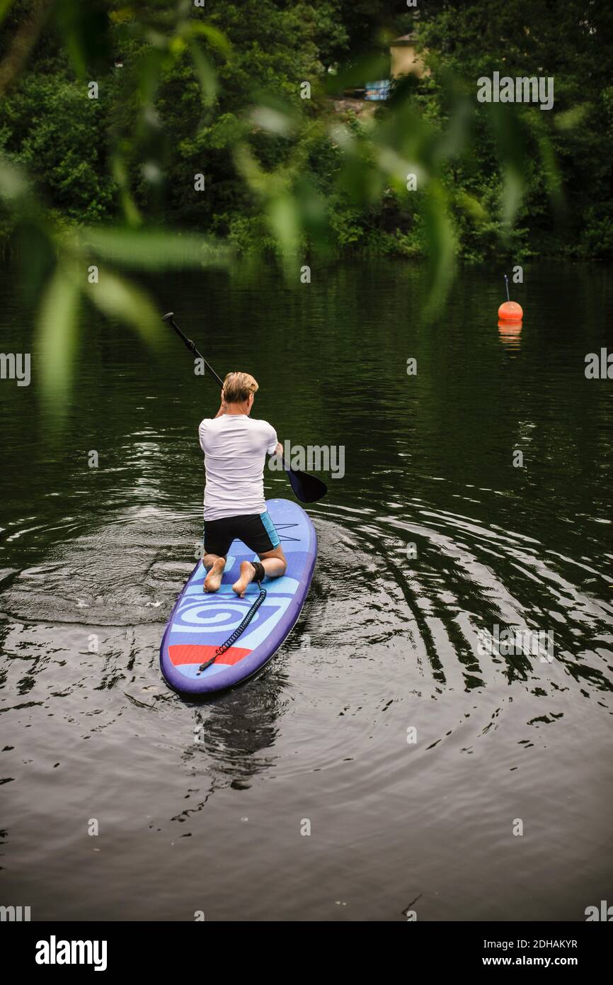 Vue arrière de l'homme senior paddleboard en mer pendant le SUP cours Banque D'Images