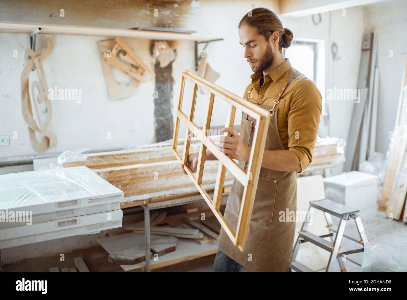 Beau menuisier vérifiant la qualité du cadre de la fenêtre avant la peinture à l'atelier de menuiserie Banque D'Images