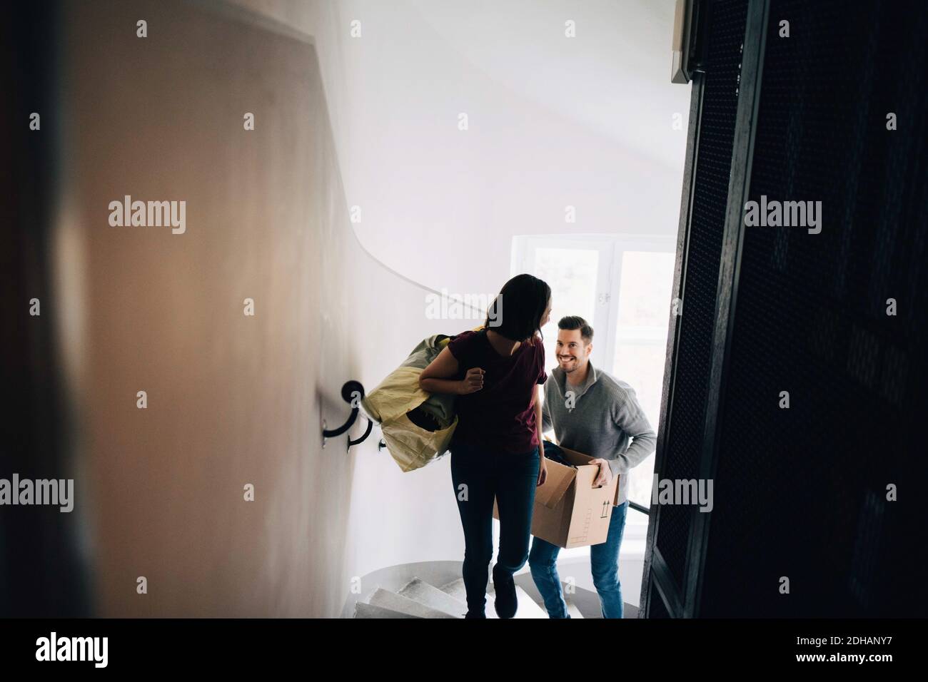 Vue en grand angle de la sacoche et de la boîte de transport du couple pendant monter les marches Banque D'Images