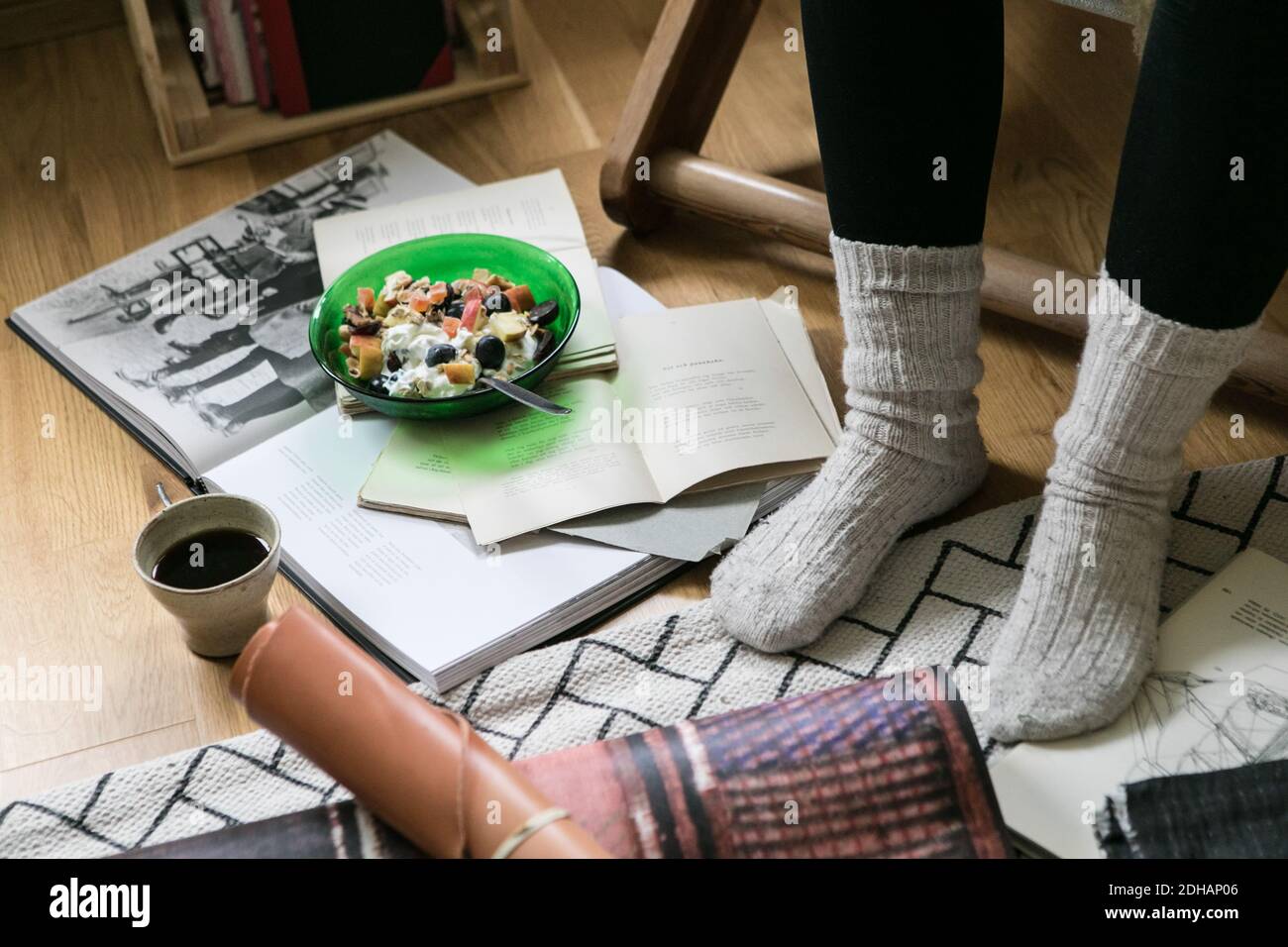 La section basse de femme d'affaires portant des chaussettes tout en se tenant près du petit déjeuner et livres au bureau à domicile Banque D'Images