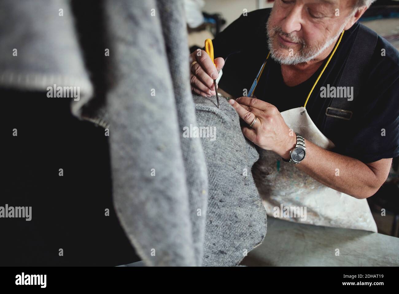 Gros plan de l'artisan principal travaillant sur le tissu gris à l'atelier Banque D'Images