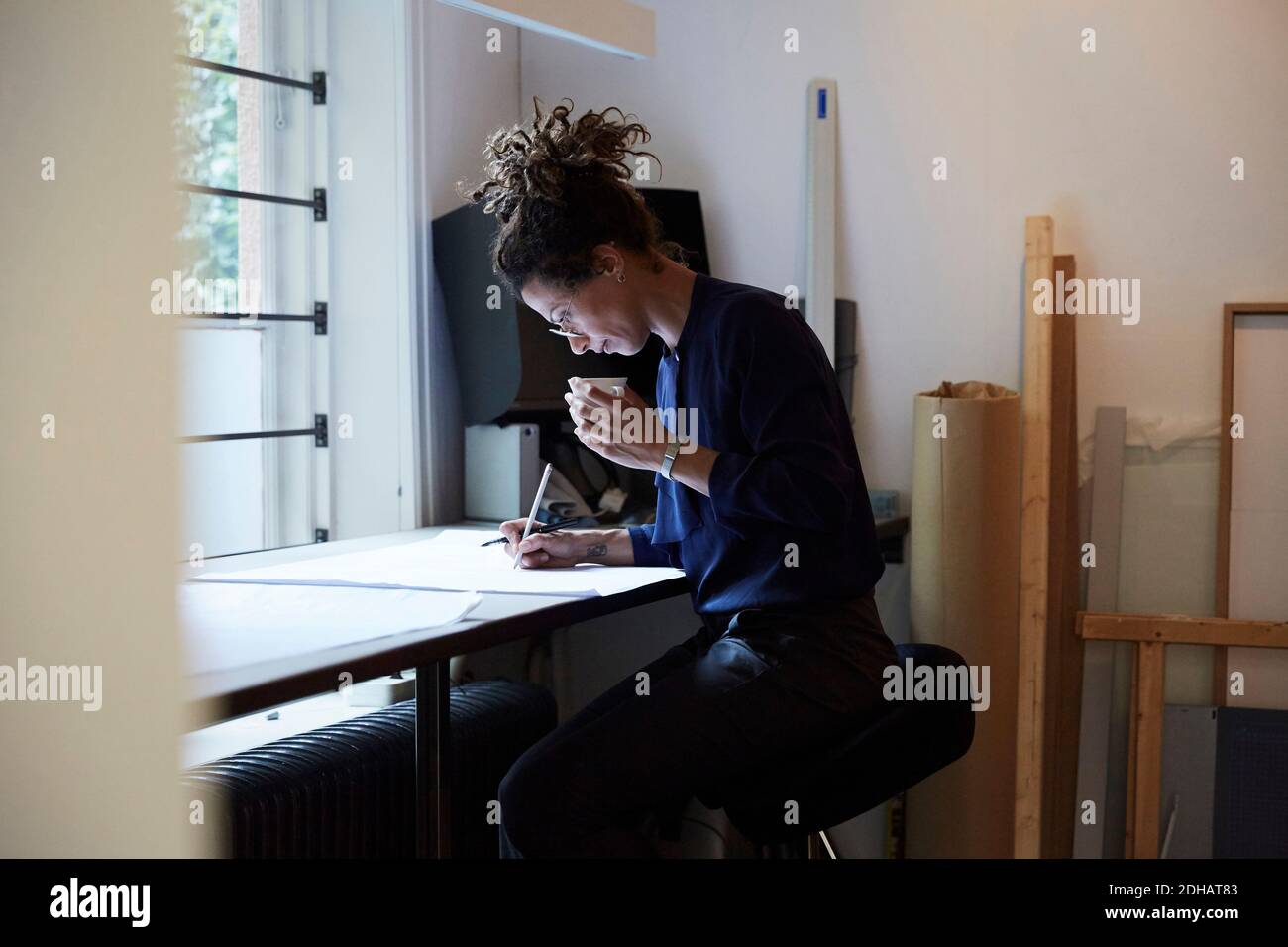 Vue latérale d'une femme architecte confiante travaillant à la table bureau Banque D'Images