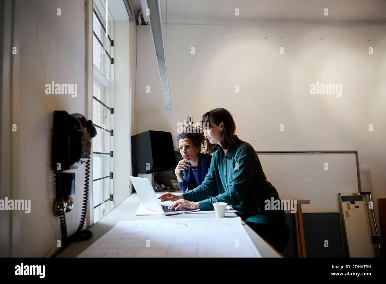 Femmes architectes discutant sur ordinateur portable à table au bureau Banque D'Images