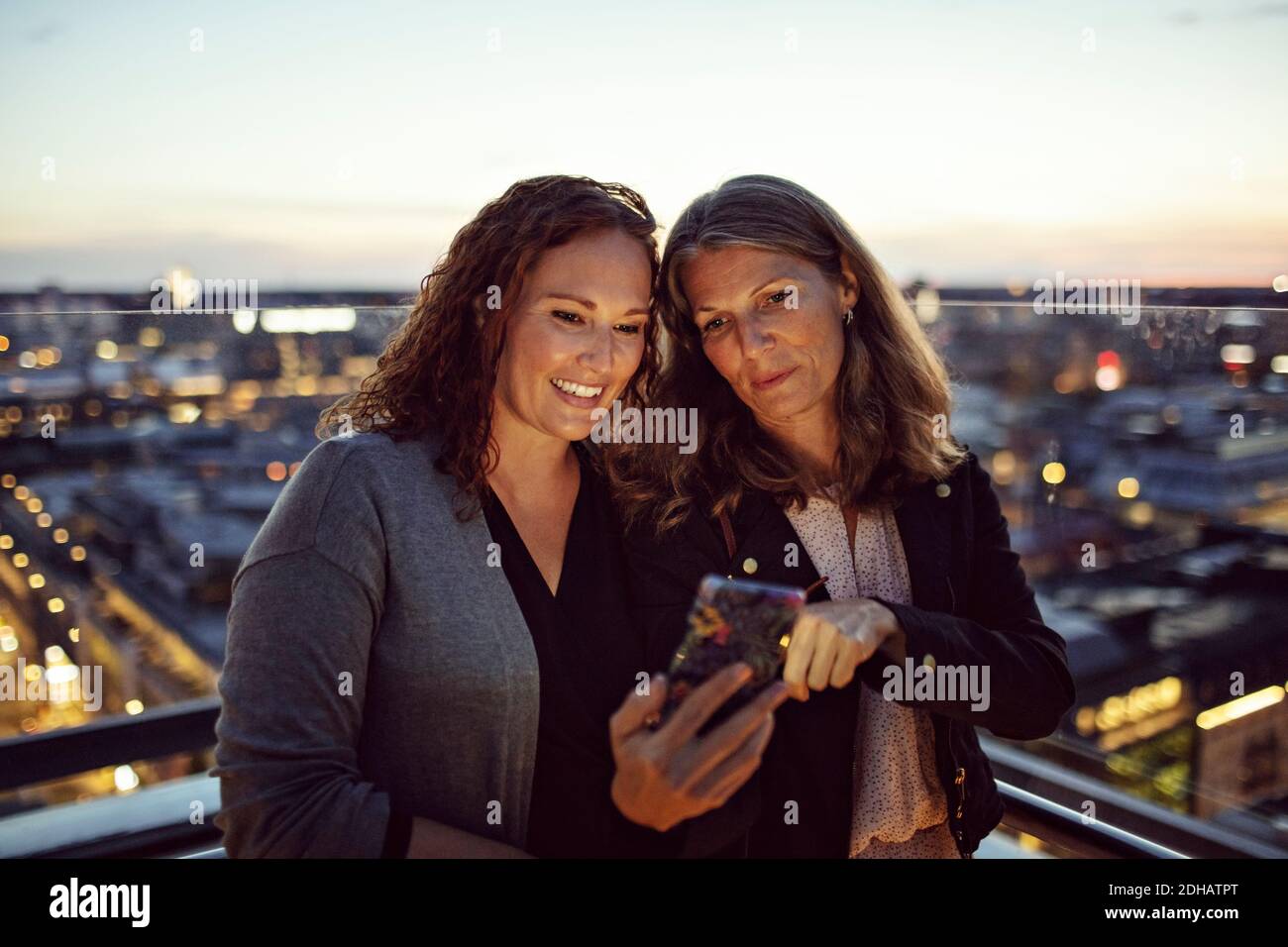 Femmes d'affaires qui prennent le selfie sur un téléphone intelligent en se tenant debout sur la terrasse après le travail Banque D'Images